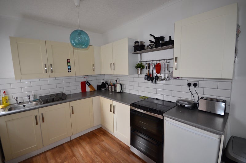 Shared kitchen with cream cabinets and grey worktops